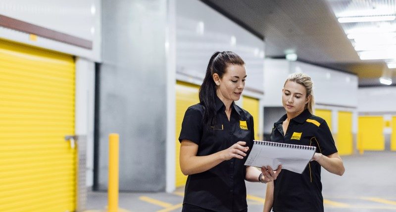two females looking at a clipboard working for national storage