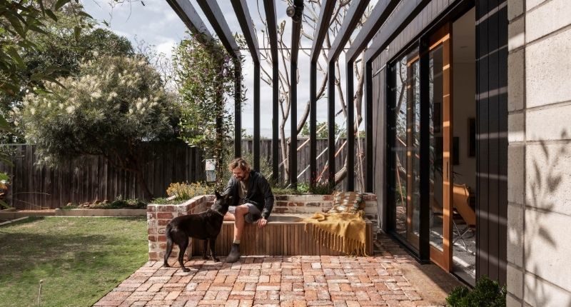 man with dog sitting at house garden