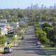 Residential houses street against Brisbane City skyline